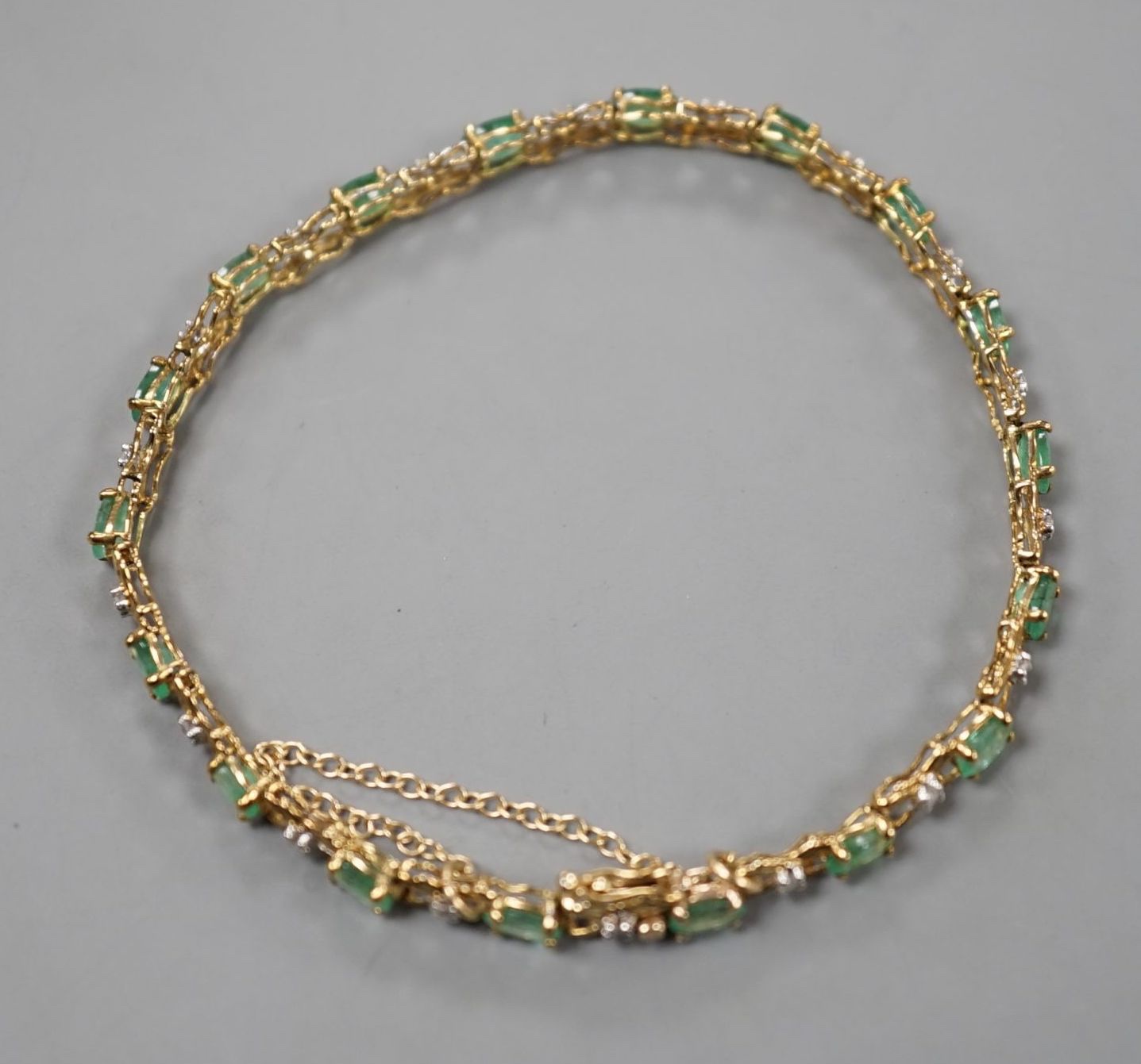 A modern 9ct gold, emerald and diamond chip set line bracelet, approx. 17cm, gross weight 5 grams.